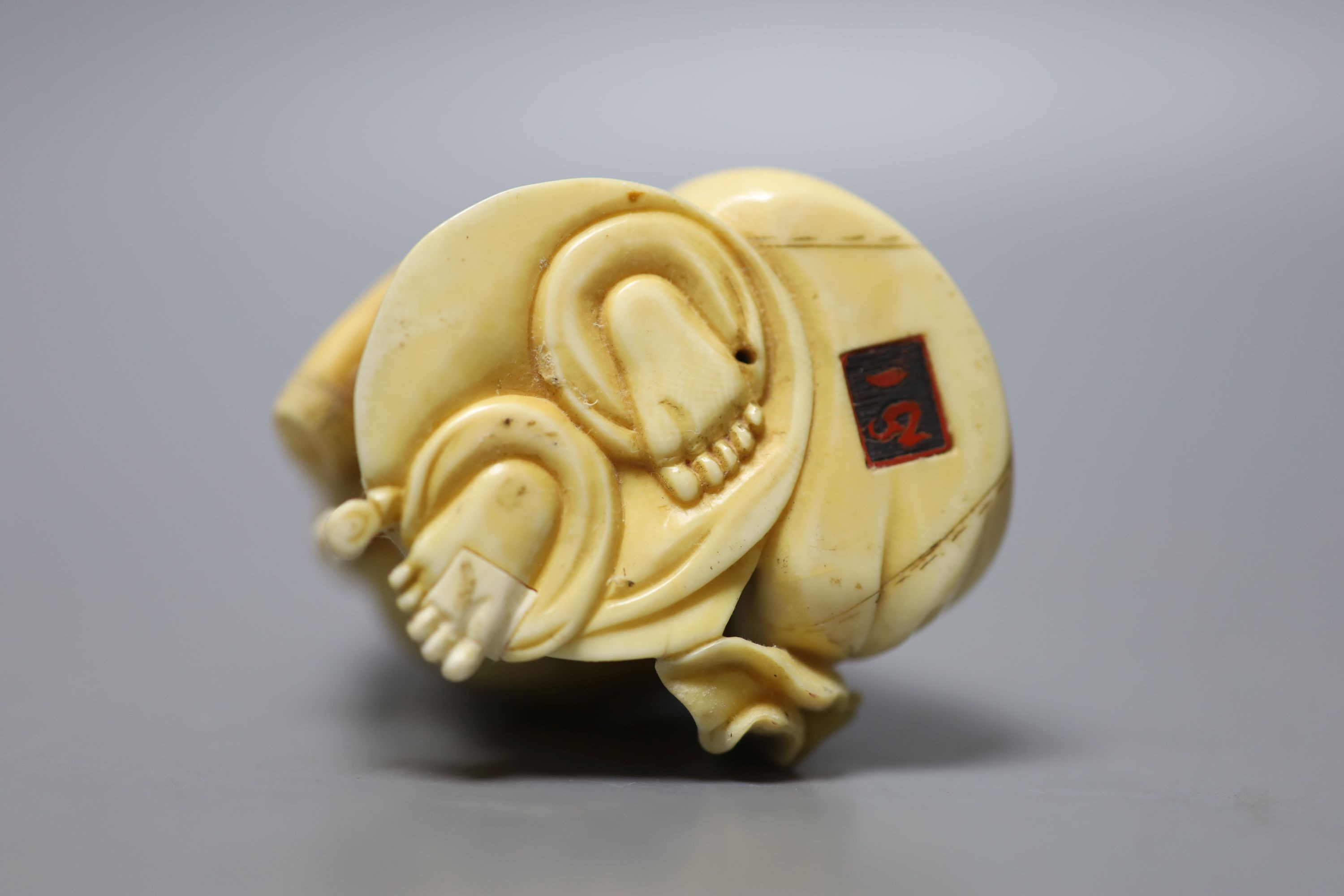 An early 20th century Japanese carved ivory okimono of Hotei, and wood stand, 15cm